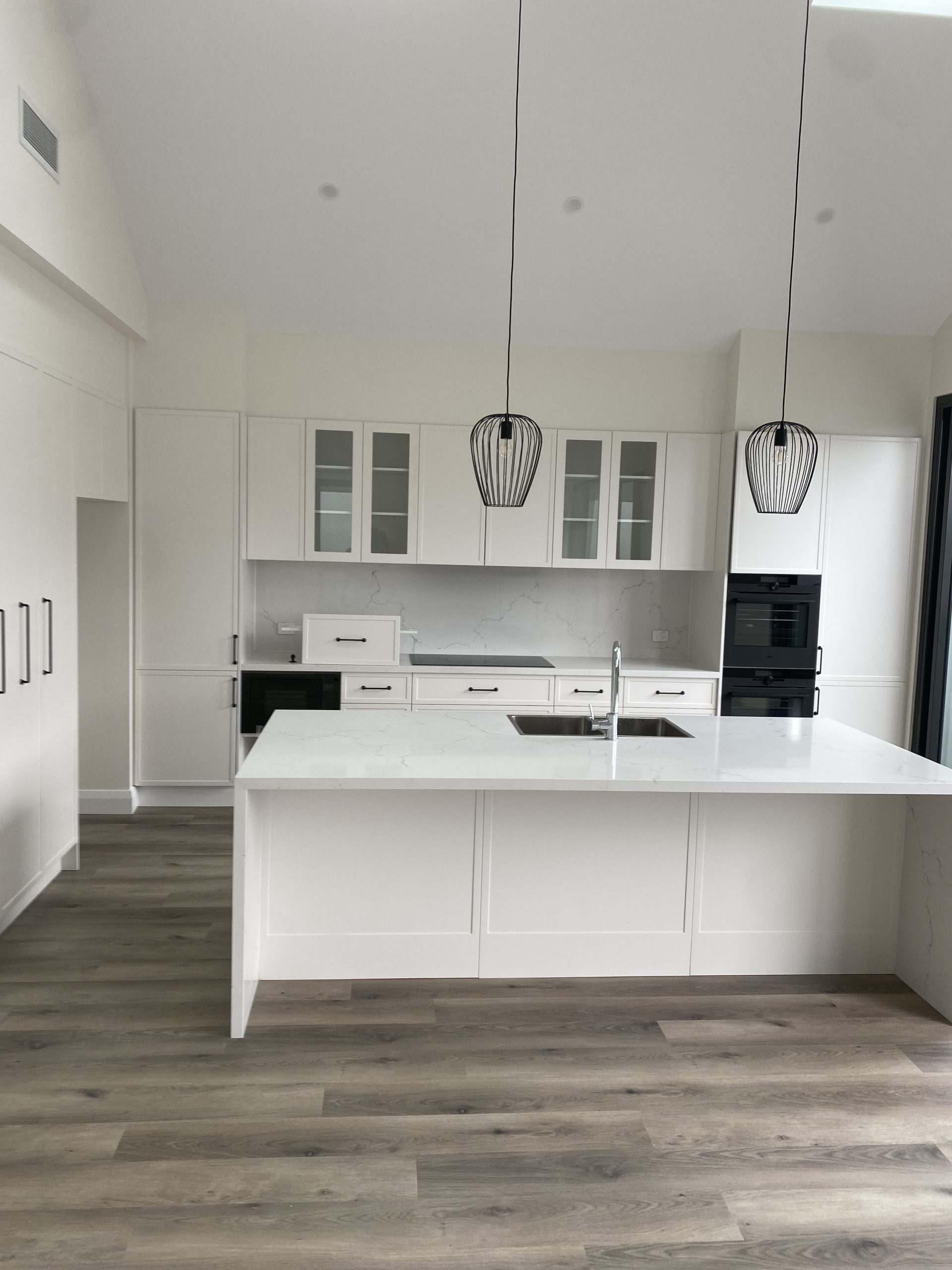 light wood-look floor, and two black wire-frame pendant lights.