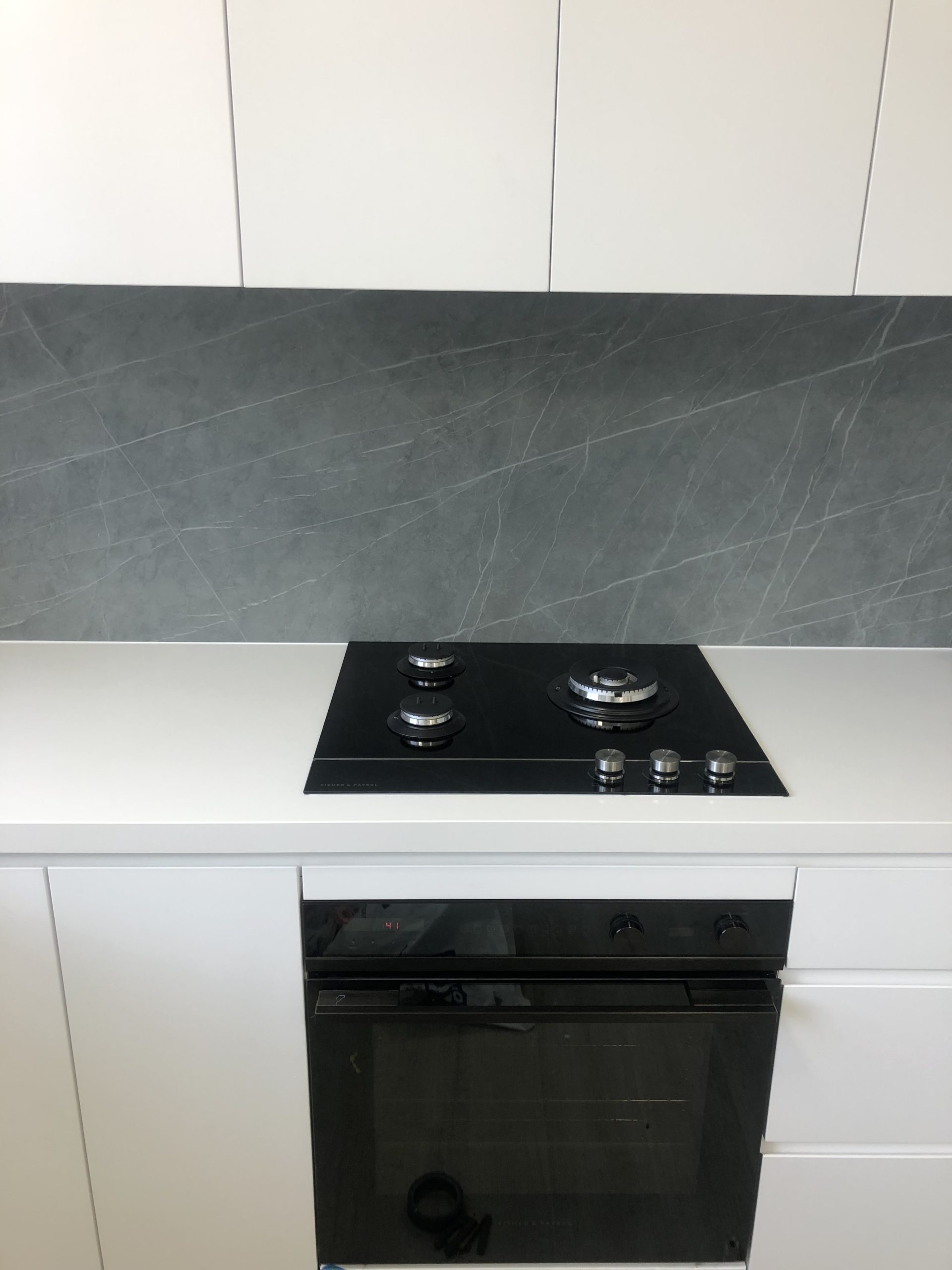 Close-up of a black gas cooktop and built-in oven installed on a white kitchen counter