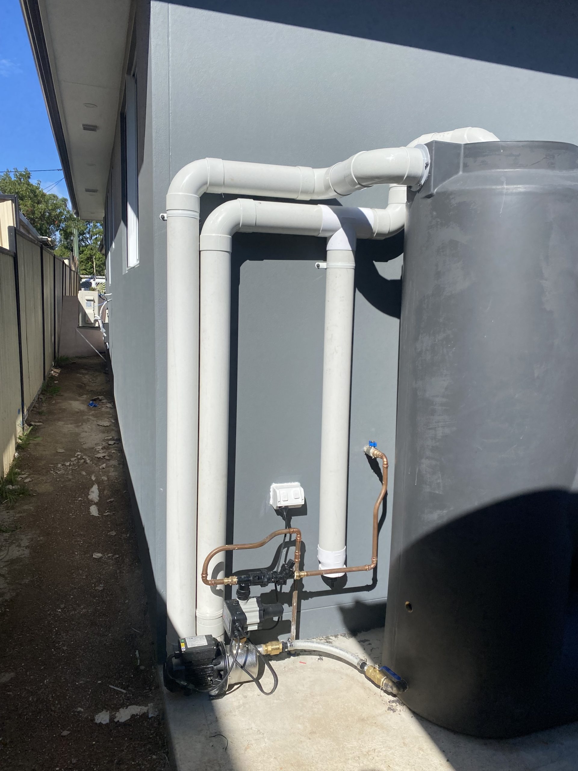 Outdoor utility area showing a black rainwater storage tank